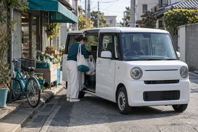 Honda N-Box: женщина ставит покупки в белый кей-кар с открытой сдвижной дверью на японской улице