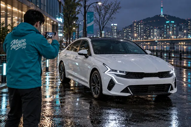 Kia K5: сотрудник МироМобиля фотографирует белый седан третьего поколения на вечерней улице Сеула